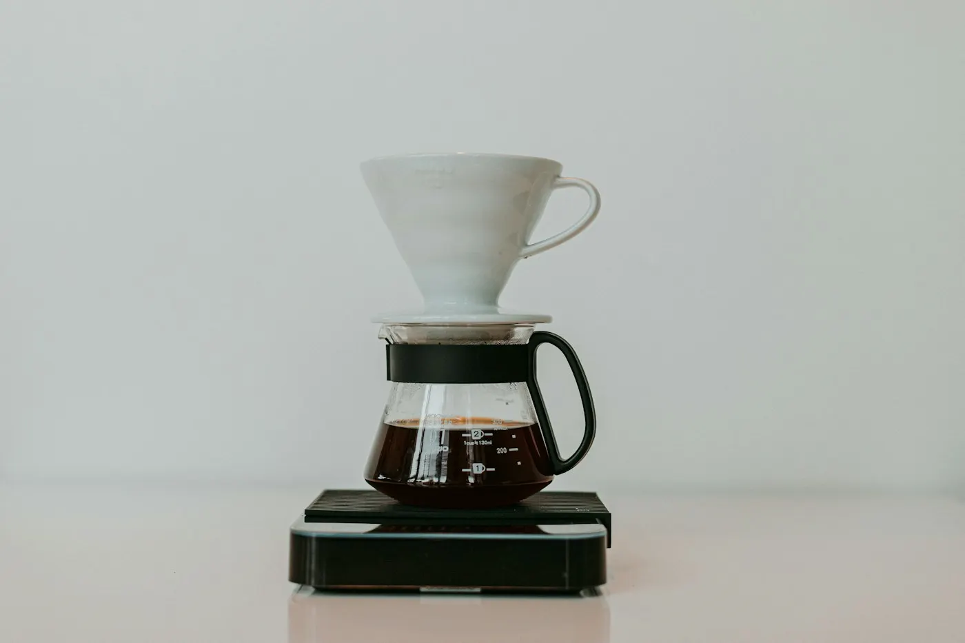 スケールの上で、ドリッパーからサーバーへ落ちるコーヒー
