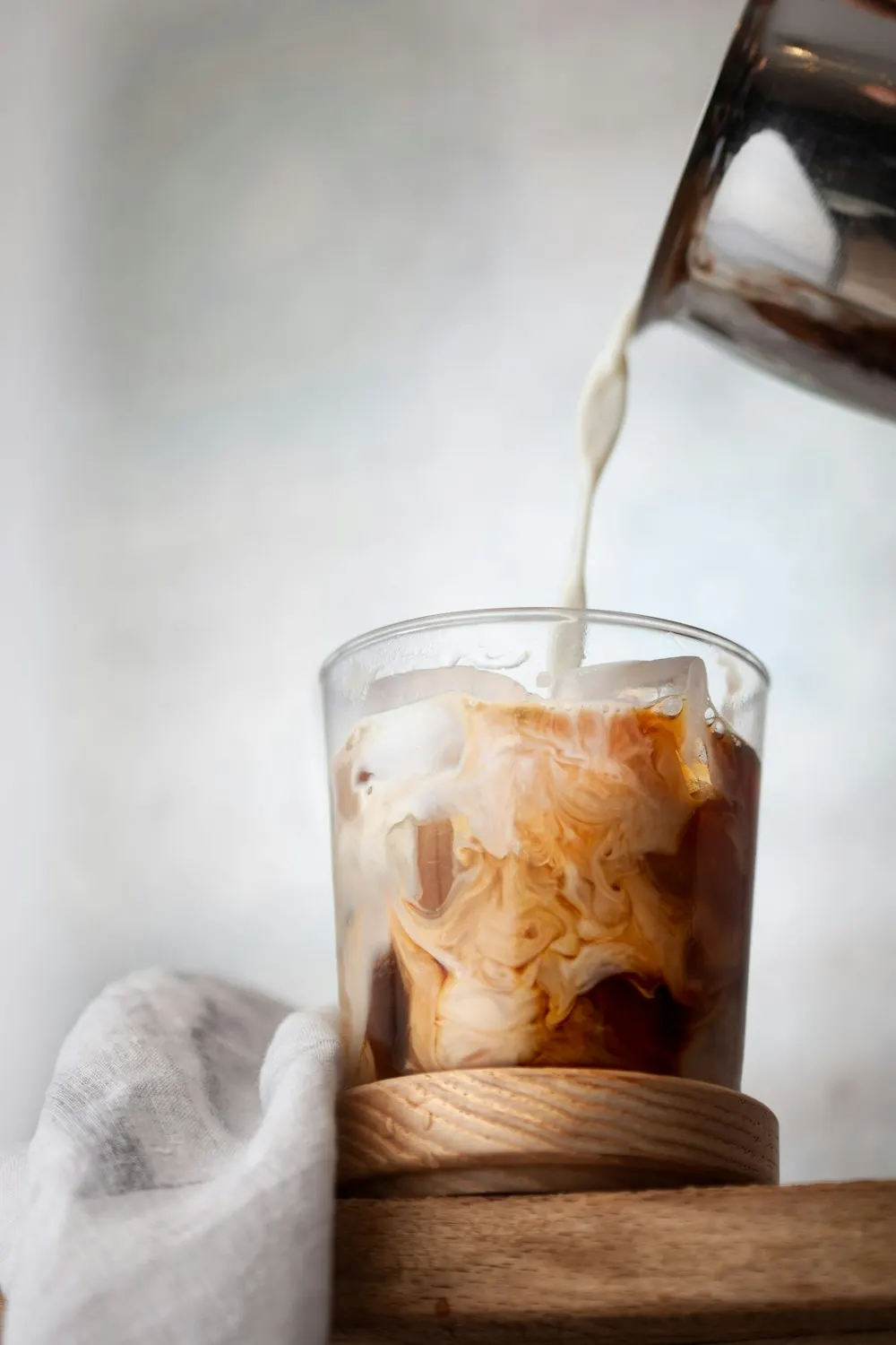 氷の入ったグラスのコーヒーに、ミルクを注いでいるところ